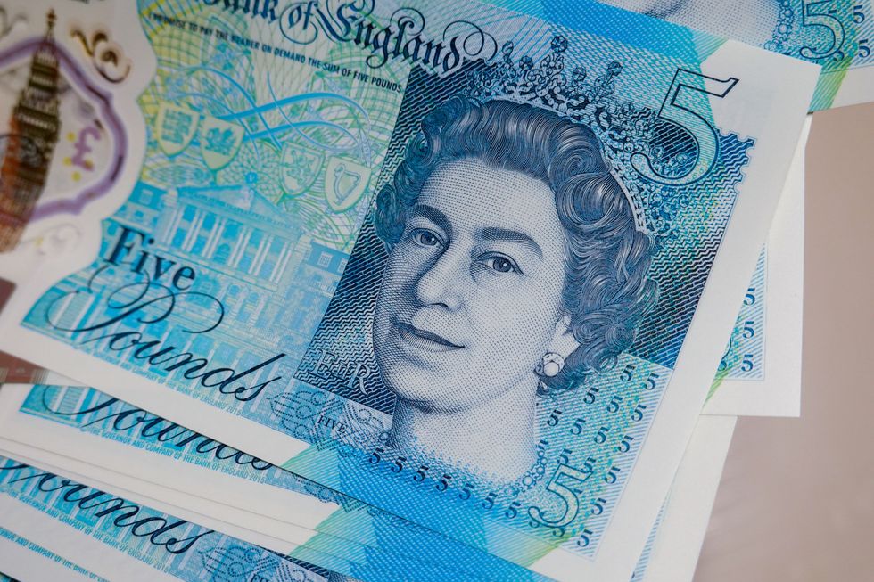 5 pounds banknotes with Queen Elizabeth II are displayed on a table
