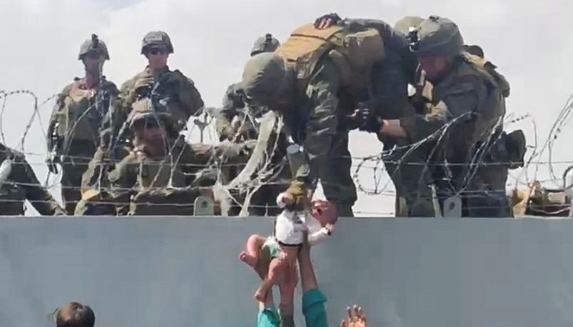 A baby is handed over to the American army over the perimeter wall of the airport for it to be evacuated, in Kabul, Afghanistan, August 19, 2021. OMAR HAIDARI/via REUTERS/File Photo