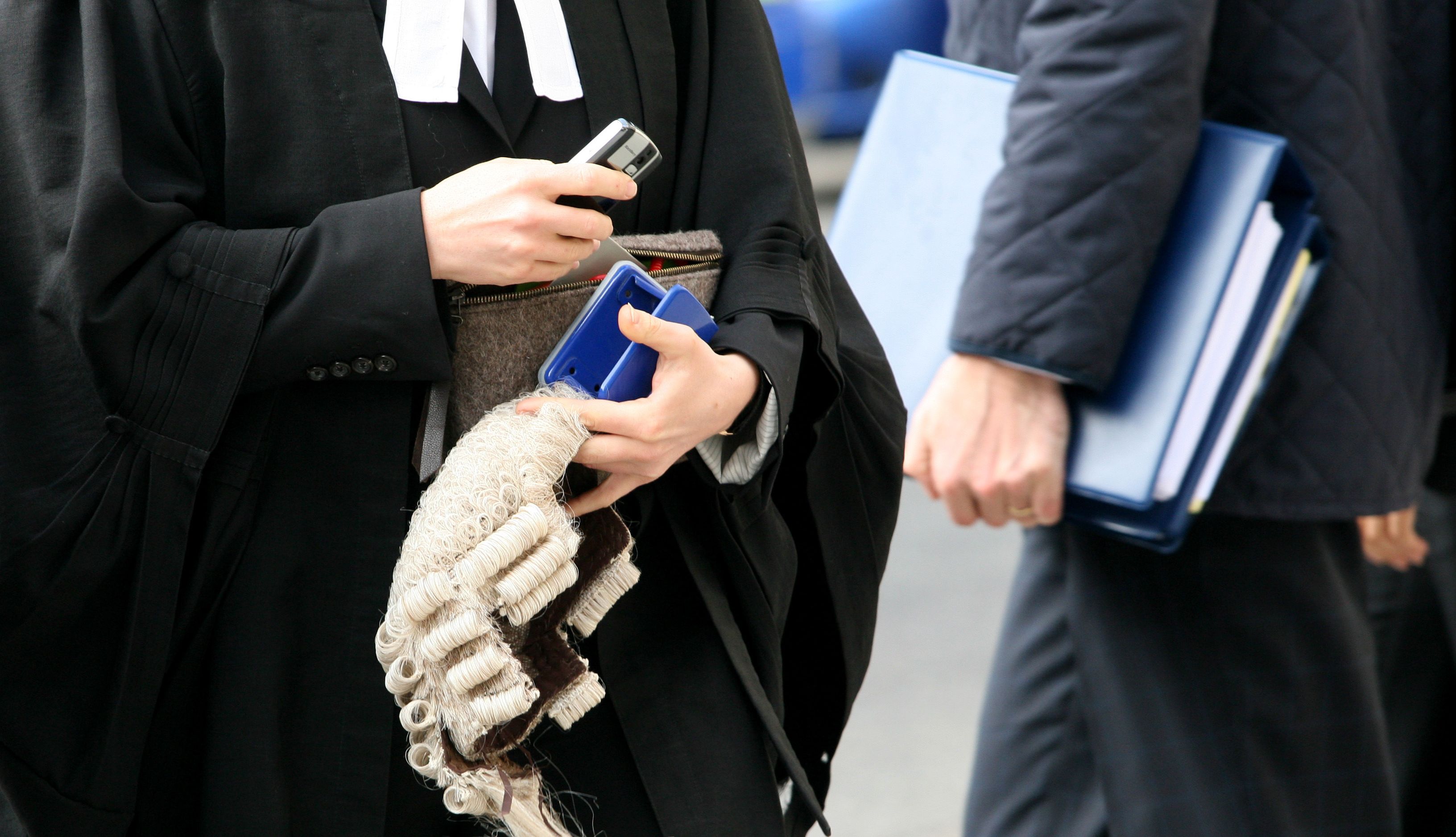 A barrister carries a wig into the Royal Courts of Justice, London.