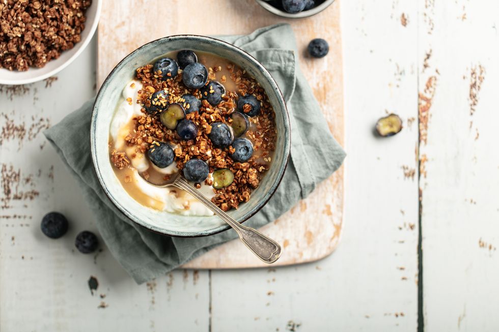 A bowl of yoghurt with granola, honey and berries