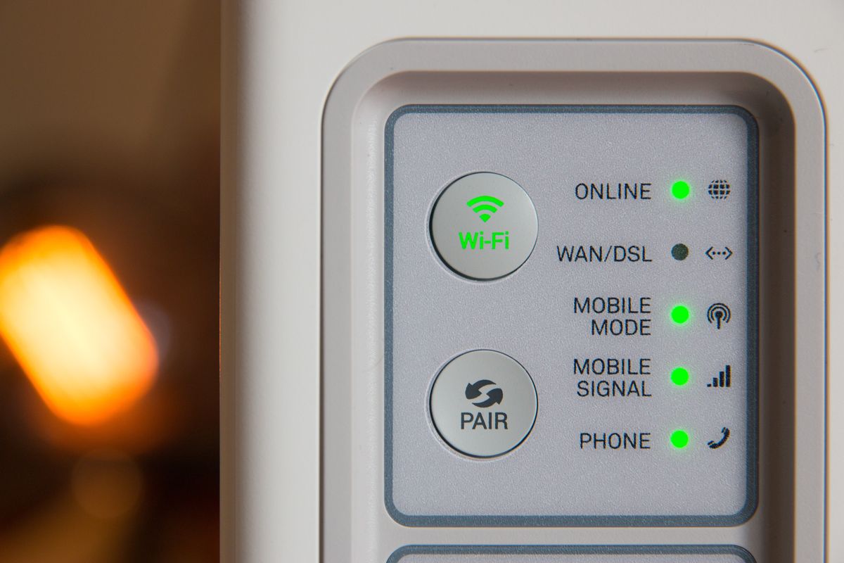 a broadband router is pictured with blinking lights for Wi-Fi to show that its online 