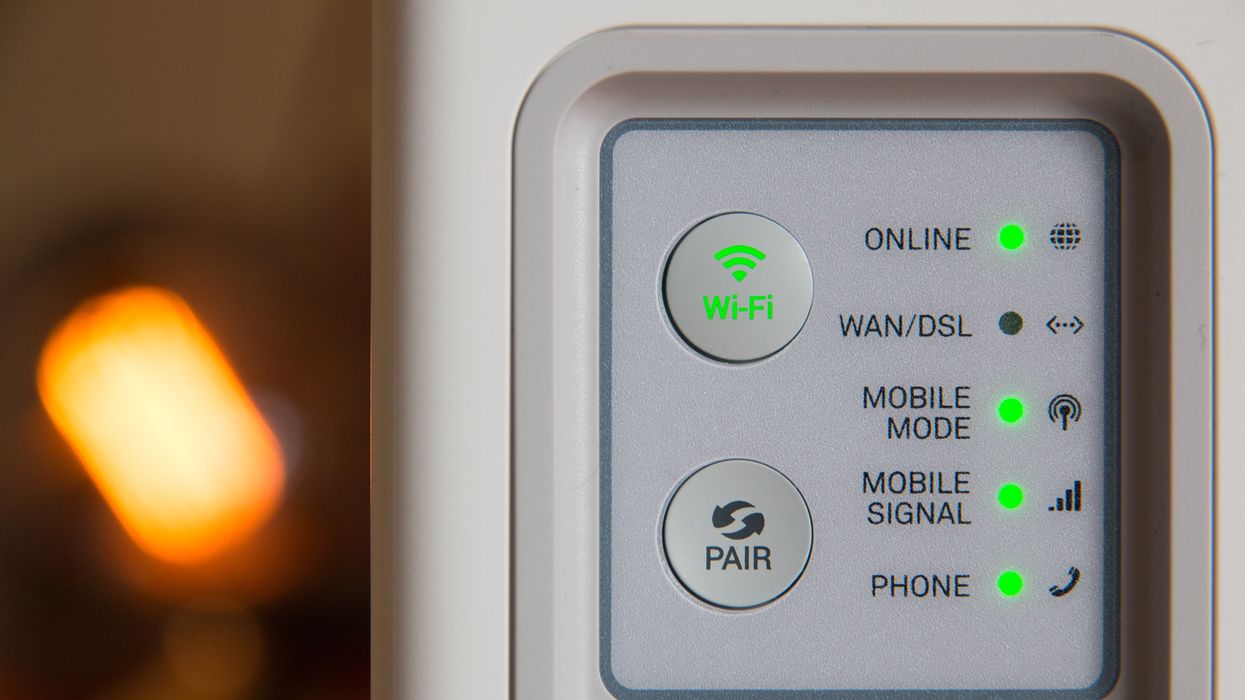 a broadband router is pictured with blinking lights for Wi-Fi to show that its online