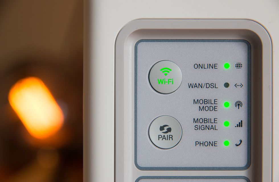 a broadband router is pictured with blinking lights for Wi-Fi to show that its online 