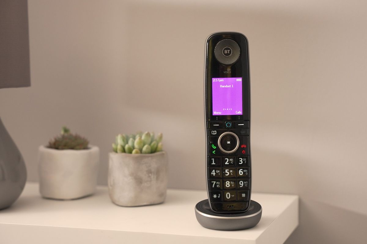 a bt digital voice handset is pictured on a sideboard with plants and a lamp