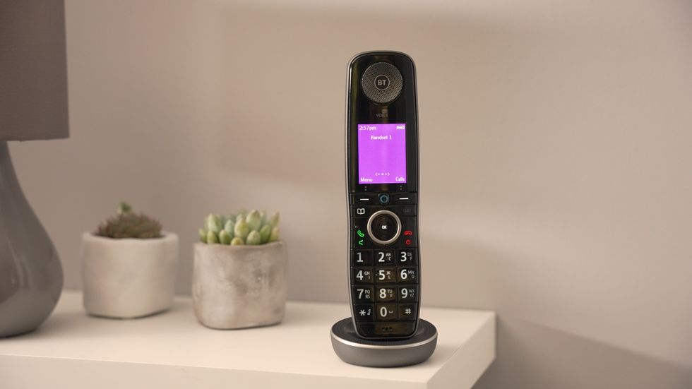 a bt digital voice handset is pictured on a sideboard with plants and a lamp