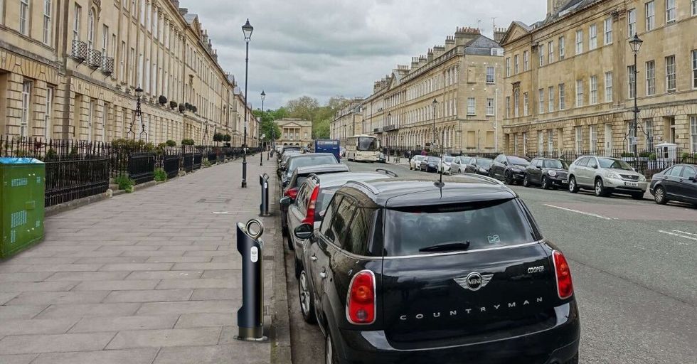 A BT electric vehicle charger with a green street cabinet in the background