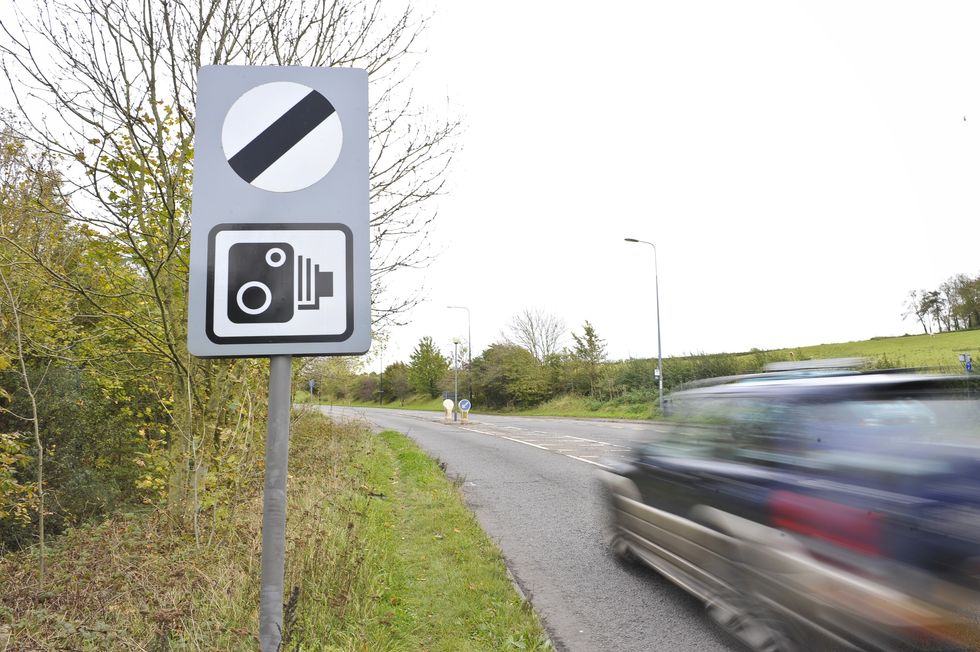 A car driving past a national speed limit sign.