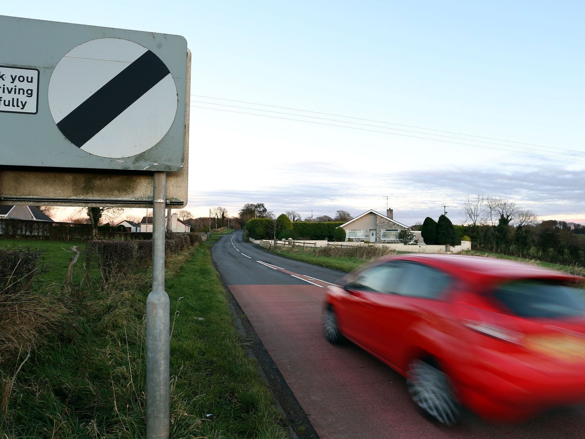 A car driving past a national speed limit sign