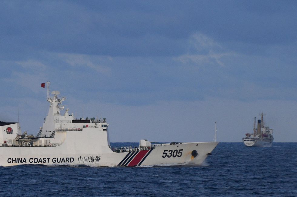 A Chinese Coast Guard ship sails near a Philippine vessel (R) that was part of a convoy of civilian boats in the disputed South China Sea