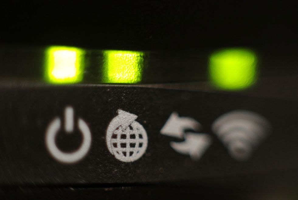 a close-up shot of a broadband router showing wifi symbol blinking green