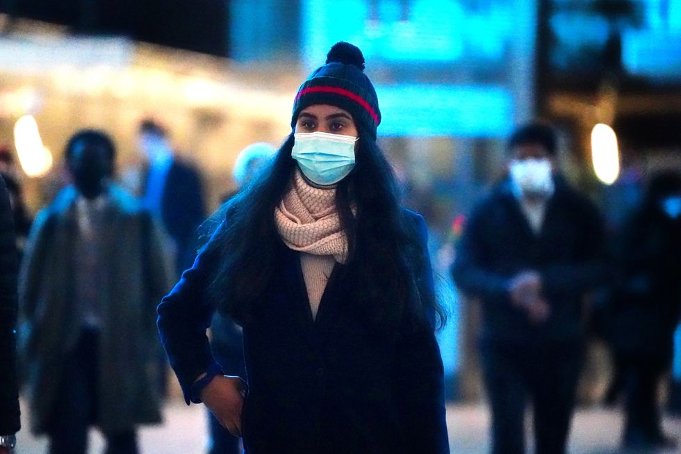 A commuter in Canary Wharf underground tube station in east London wears a face covering