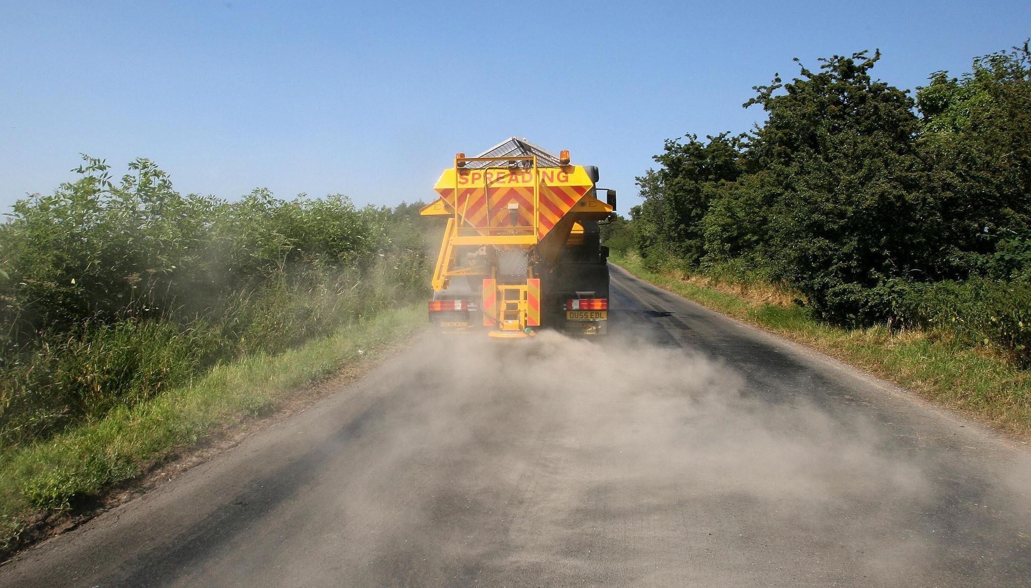 A council road gritter spreads sand on a heat-damaged road at Kirkby Thore in Cumbria in a bid to prevent the road melting in the sweltering conditions.