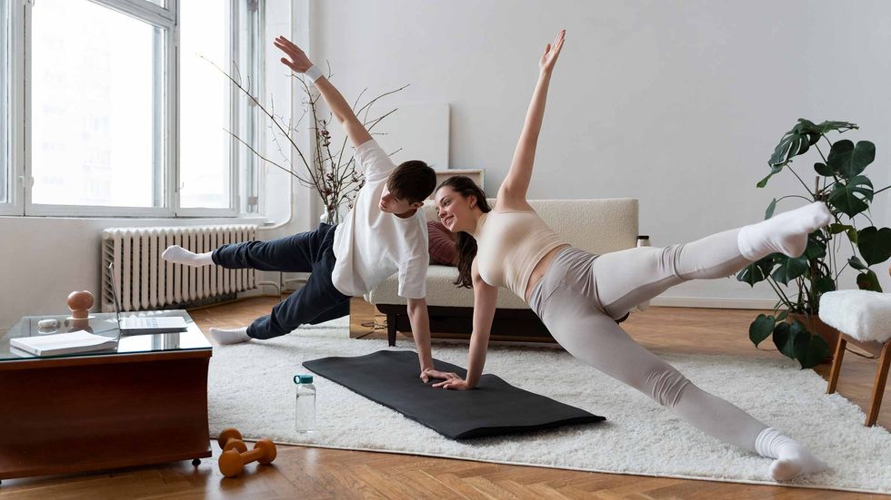 a couple in fitness gear pictured working out at home following along with Fit at Home classes