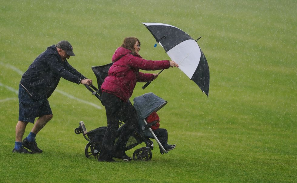 A couple navigate their way through the rain with their toddler in a ush chair