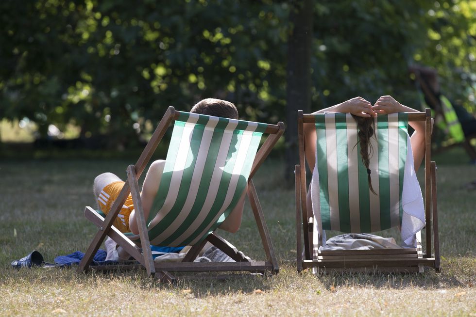 A couple relax on deckchairs in the warm weather in Hyde Park