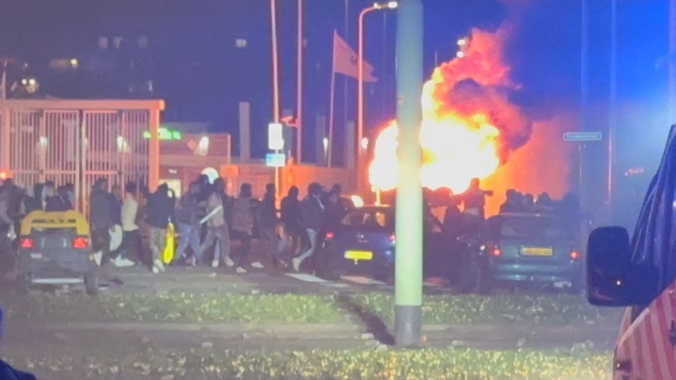 A crowd gathers near a burning vehicle after a meeting of the Eritrean community ended in violence