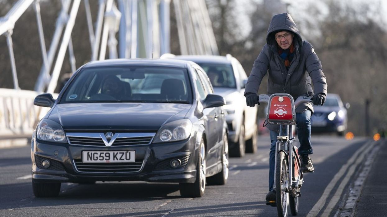 A cyclist riding along a car