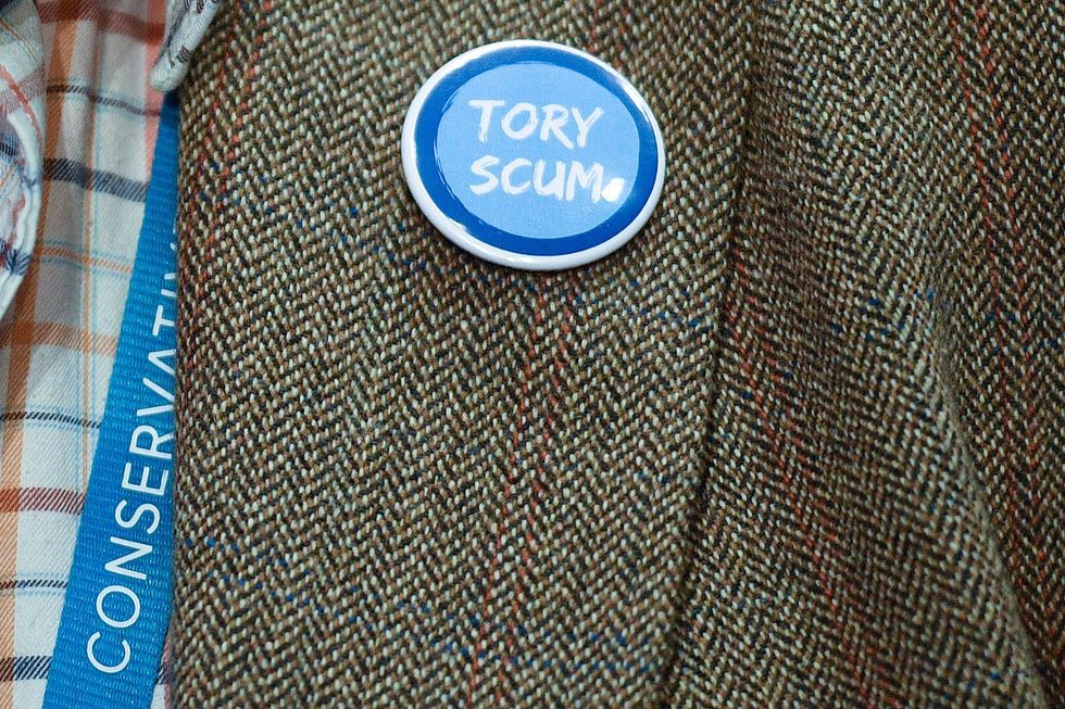 A delegate wears a "Tory Scum" lapel badge on the third day of the annual Conservative Party Conference