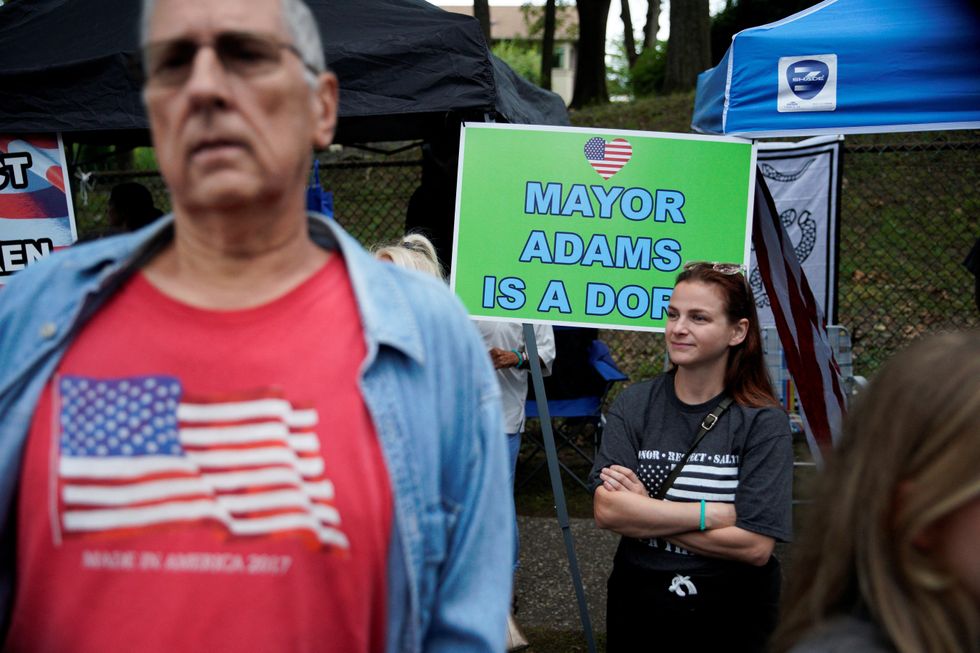 A demonstrator stands near a sign during a protest against the opening of a shelter center for recently arrived migrants to New York