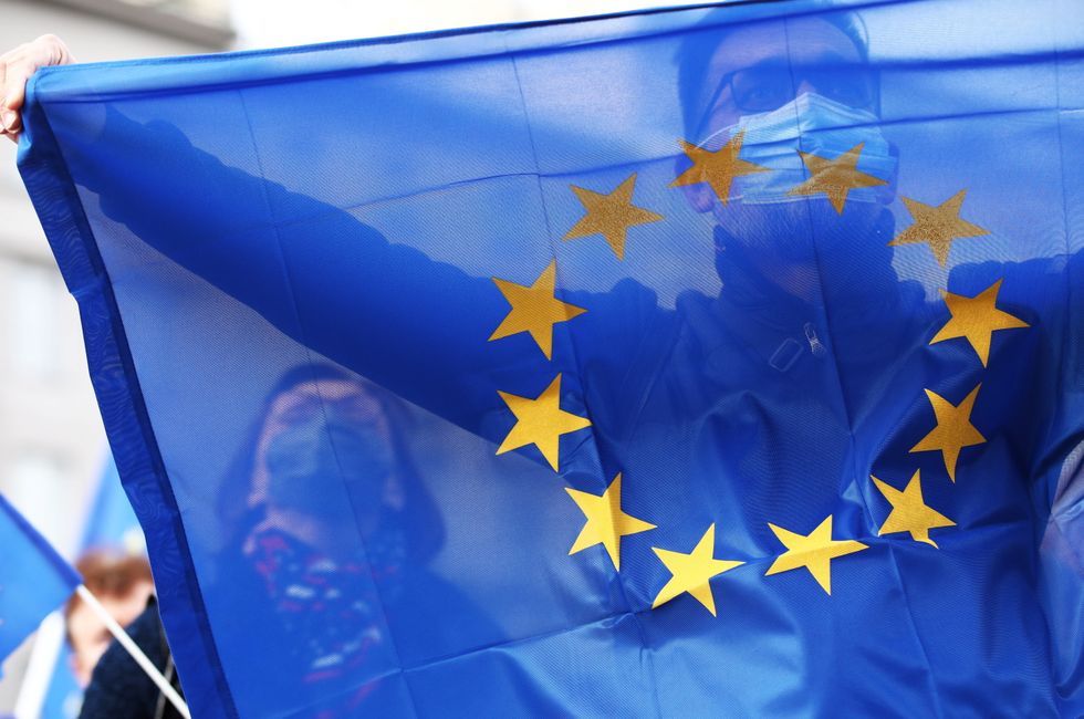 A demonstrator wearing a face mask holds the EU flag during a rally in support of Poland's membership in the European Union.