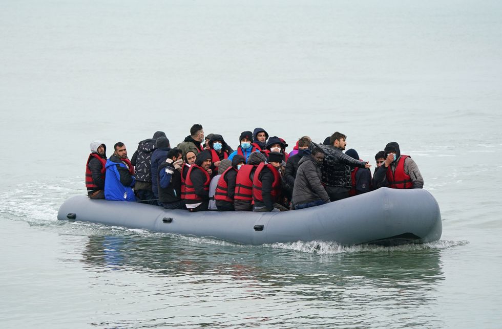 A dinghy carrying people thought to be migrants, arrives on a beach in Dungeness, Kent.