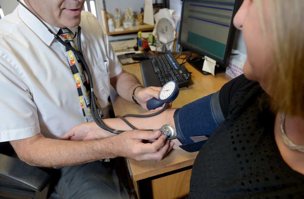 A doctor checking a patient's blood pressure in his practice room at the Temple Fortune Health Centre GP Practice near Golders Green, London