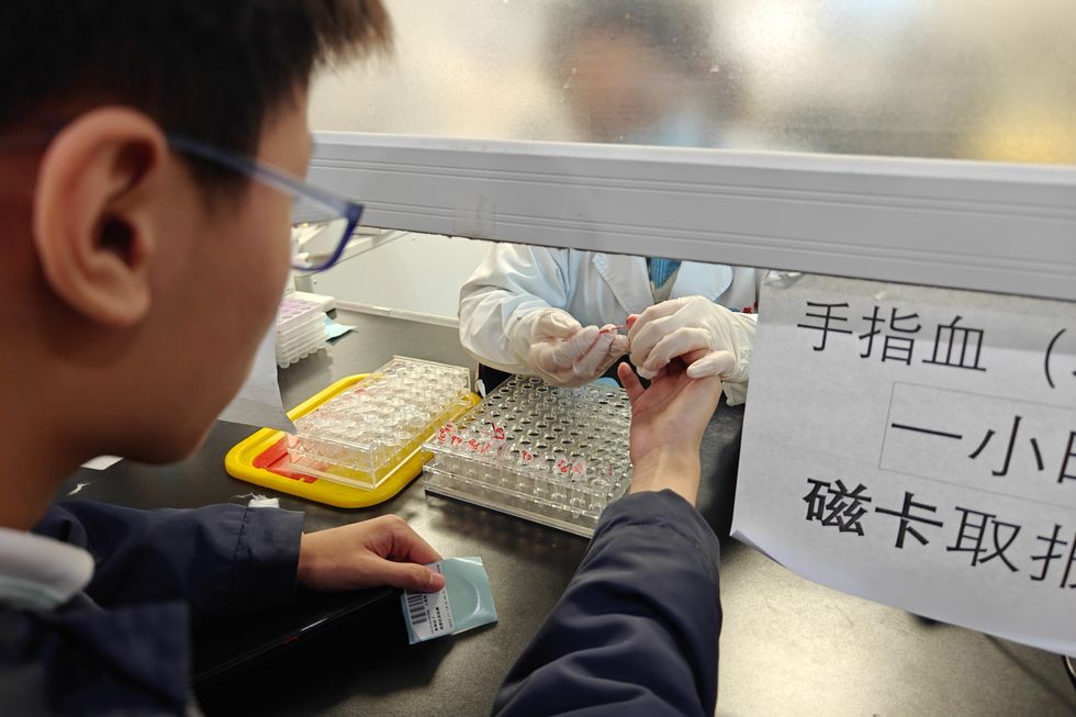 A doctor draws blood from a patient's finger at a hospital emergency department in Shanghai