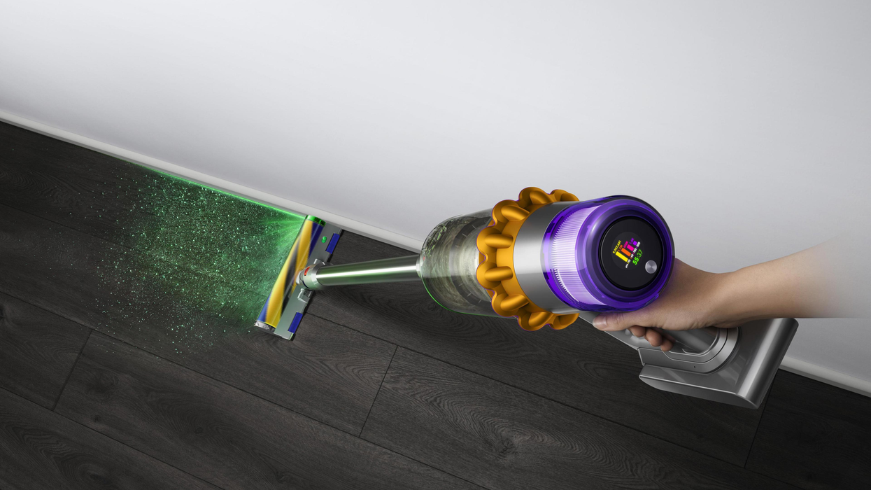 a dyson v15 detect in-use with the laser illuminating dust on the floor