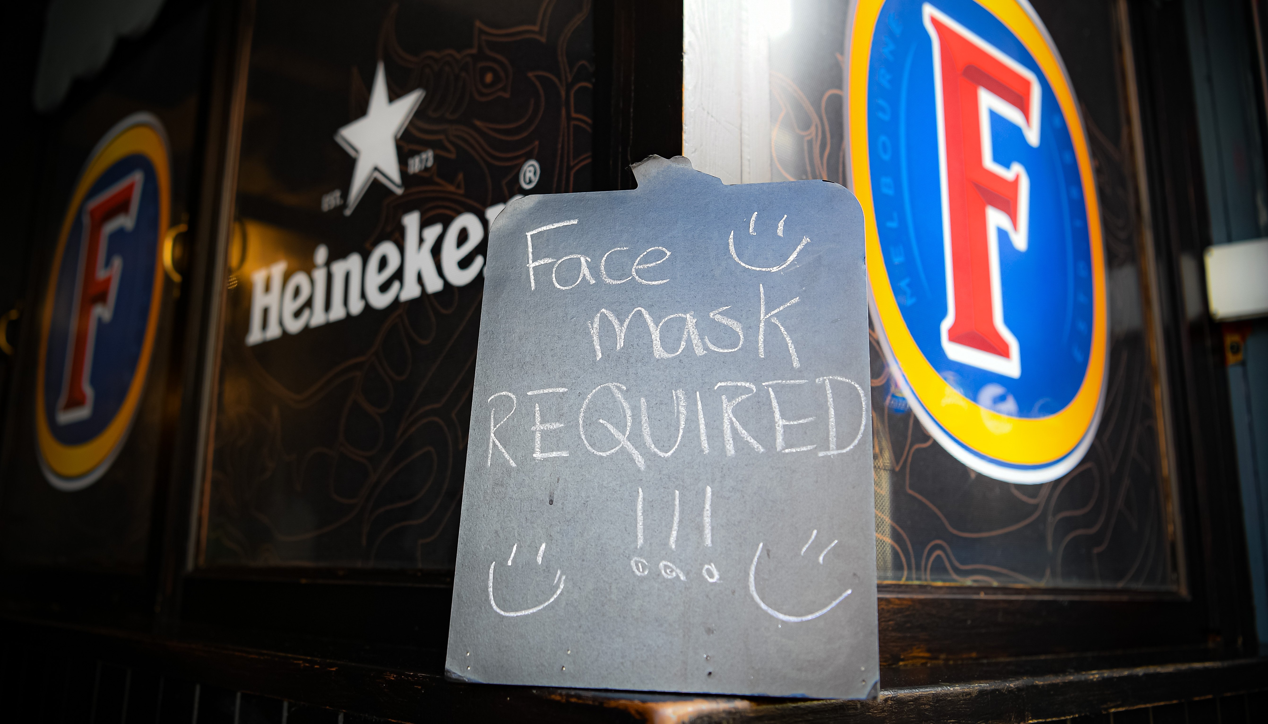 A face mask requirement sign beside alcohol branding at The Borough pub on St Mary's Street, Cardiff.