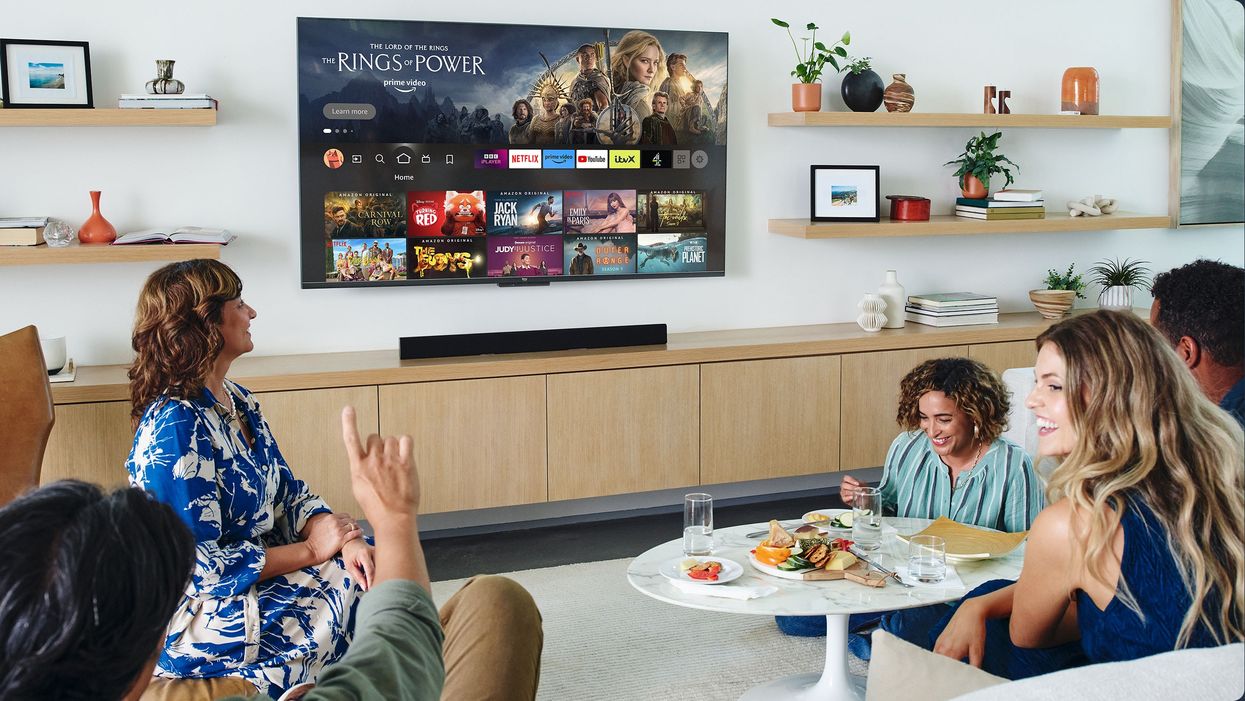 a family sit around watching prime video on a flatscreen television mounted on the wall