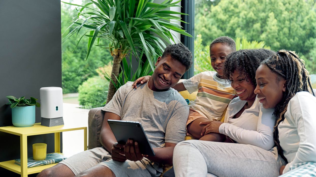 a family sit around with a tablet with the new ee wi-fi 7 router to the side