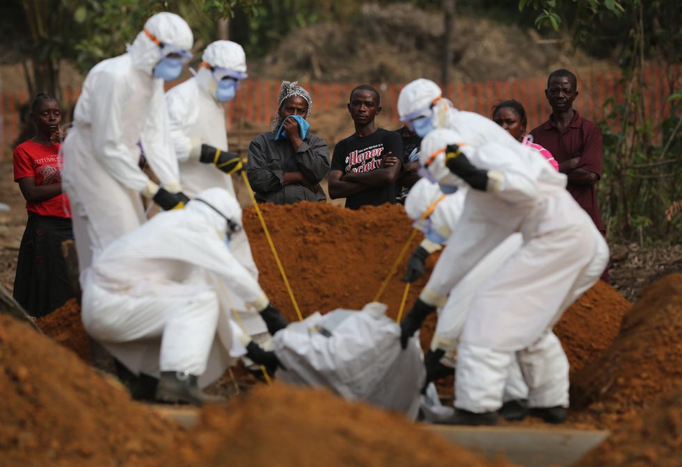 A family watches as a burial team lowers their loved one into a grave in Liberia in 2015