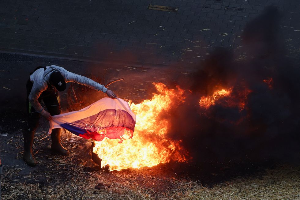 A farmer burns a Russian flag during a protest of European farmers over price pressures, taxes and green regulation, on the day of an EU Agriculture Ministers meeting in Brussels