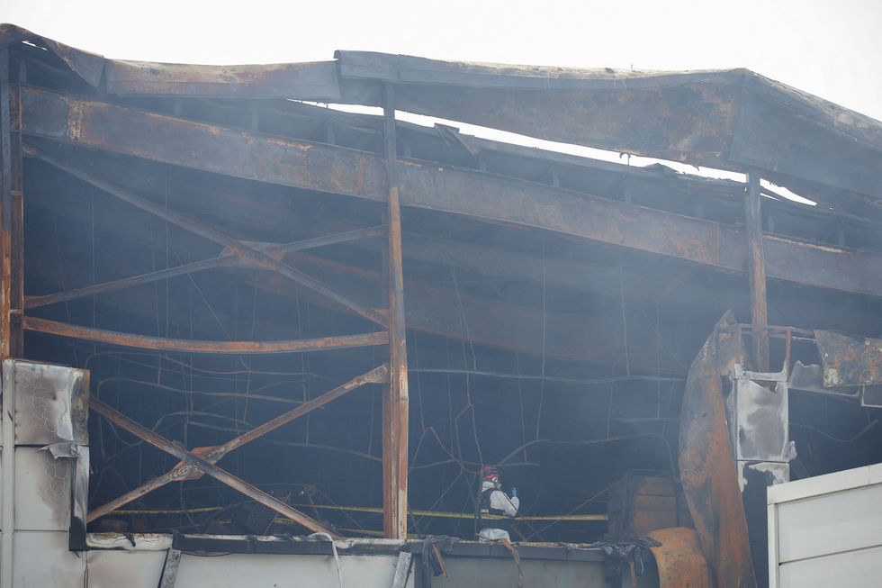 A firefighter inspects the site of a deadly fire at a lithium battery factory