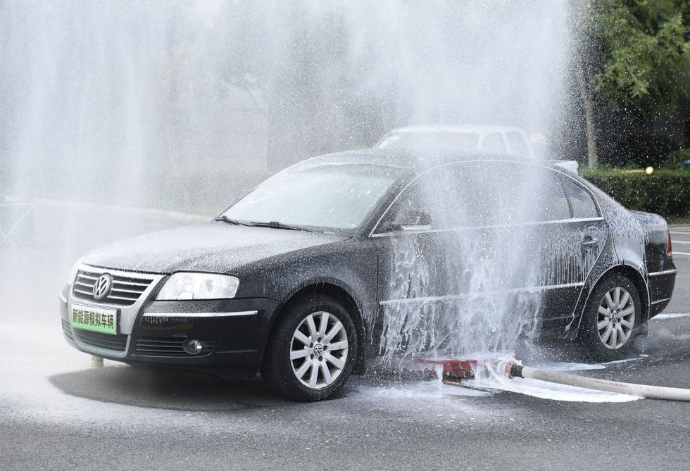 A firefighting robot is spraying water under the chassis of an electric vehicle that is simulated to be on fire and is lifting the vehicle to safety during a fire drill in Huai'an, China
