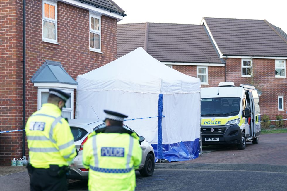 A forensic investigator outside a house in Costessey near Norwich after four people were found dead inside the property