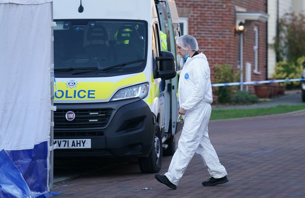 A forensic investigator outside a house in Costessey near Norwich after four people were found dead inside the property