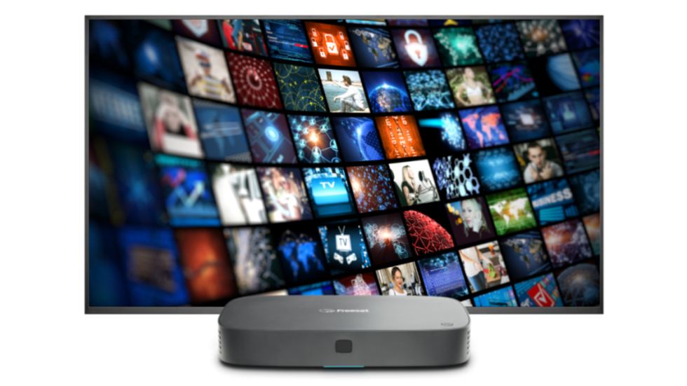 a freesat box is pictured in front of a screen filled with previews of tv shows and films