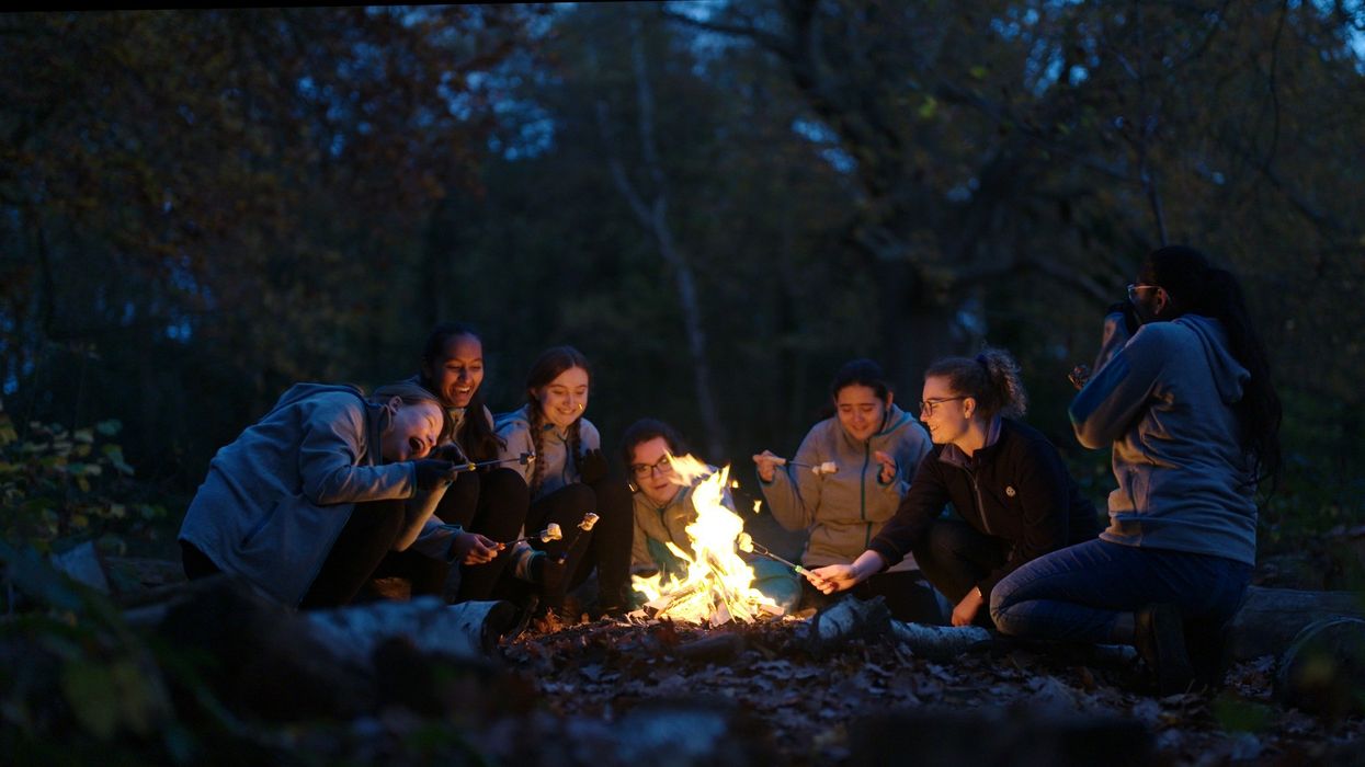 A Girl Guides group sit around a campfire