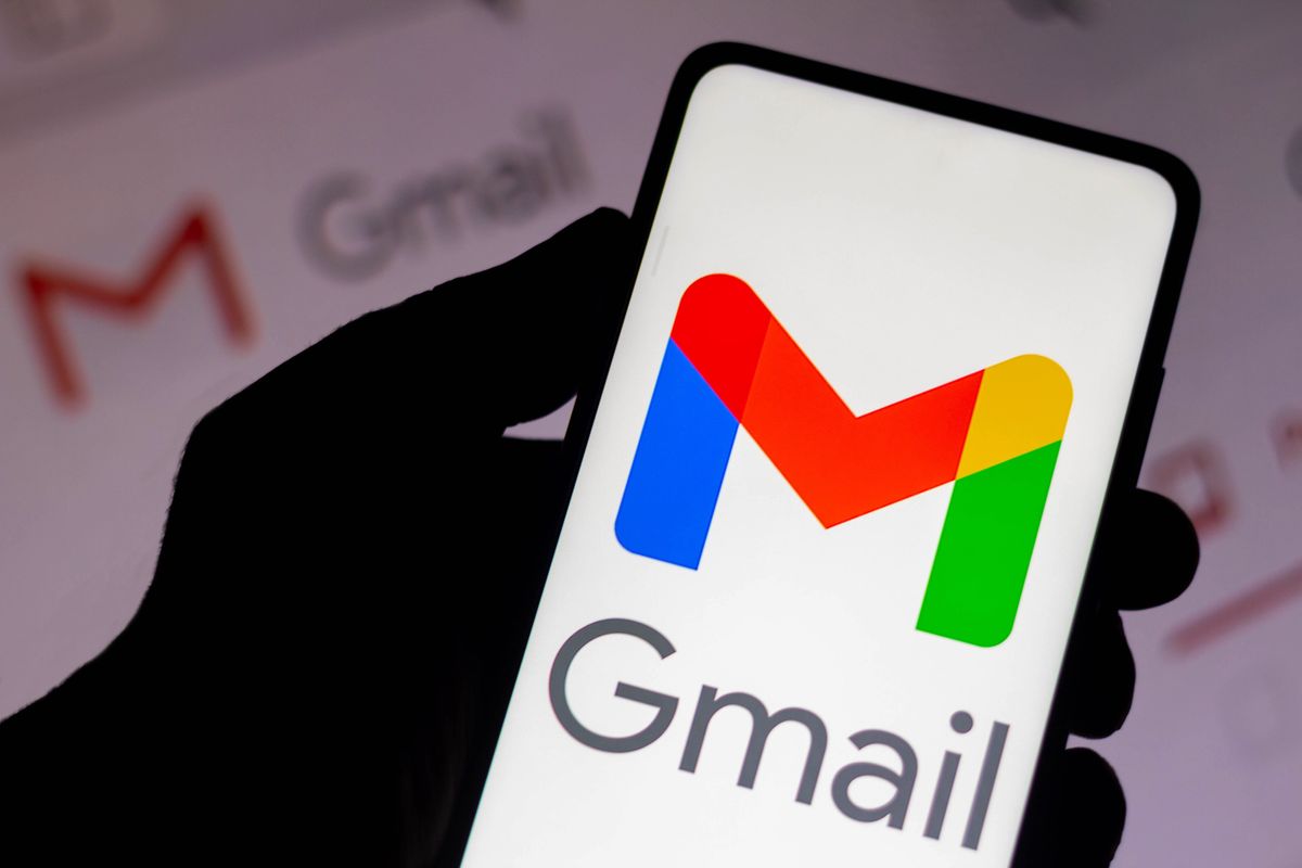 a gmail logo appears on a smartphone screen with a screenshot of an inbox in the background   