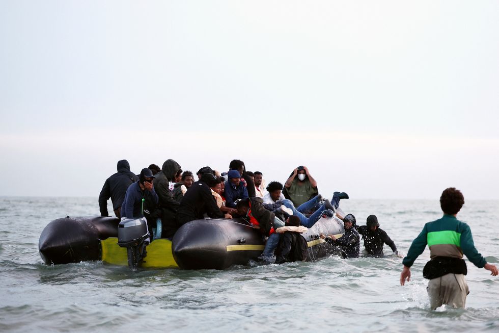 A group of migrants get on an inflatable dinghy in an attempt to cross the English Channel to reach Britain