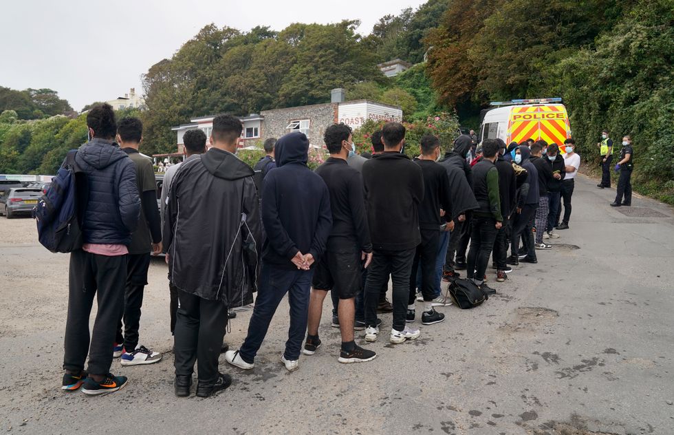 A group of people thought to be migrants are escorted by Police and Border Force officers away from the beach at St. Margaret's Bay near Dover in Kent after arriving on the beach in a small boat following a number of small boat incidents in the Channel.