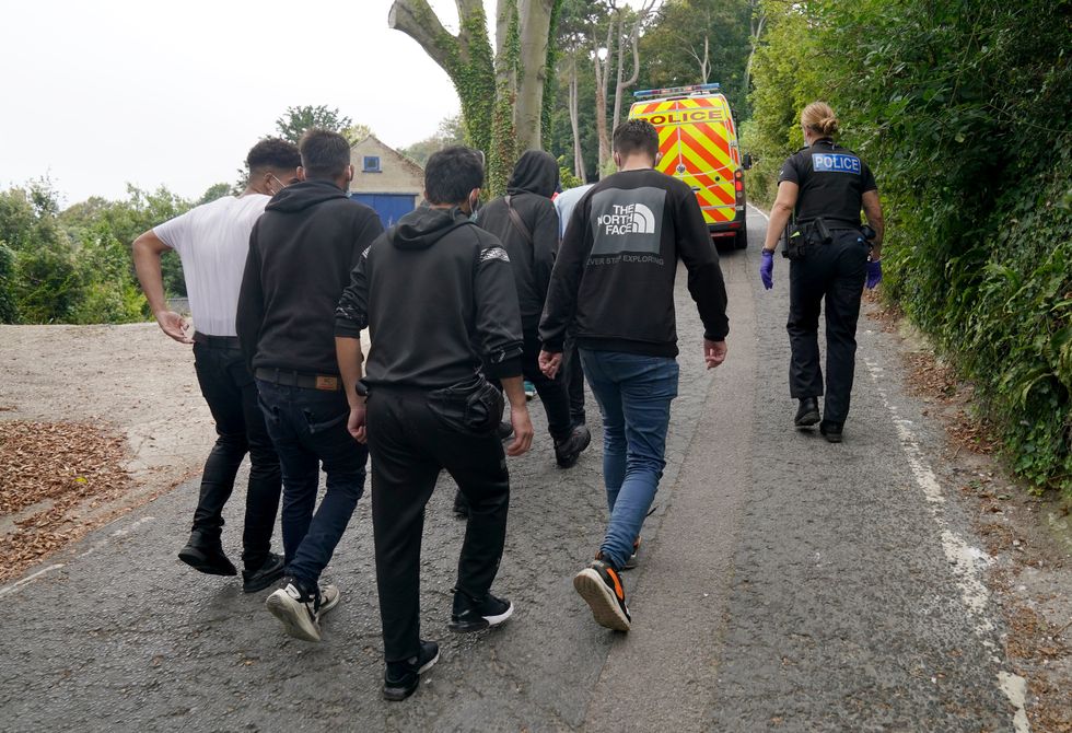 A group of people thought to be migrants are escorted by Police and Border Force officers away from the beach at St. Margaret's Bay near Dover in Kent after arriving on the beach in a small boat following a number of small boat incidents in the Channel. Picture date: Sunday September 26, 2021.
