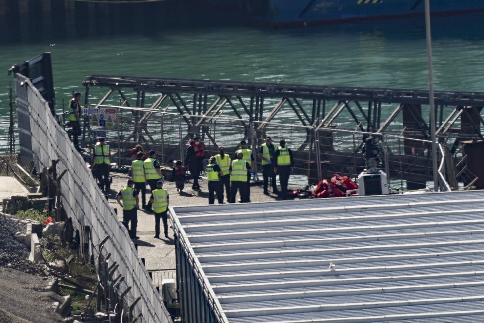 A group of people thought to be migrants disembarking a UK Border Force vessel at the Border Force compound in Dover, Kent