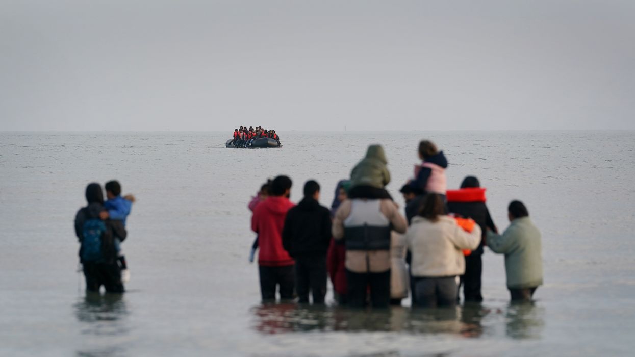A group of people thought to be migrants wait in the sea to board an approaching small boat at Gravelines, France, in an attempt to reach the UK by crossing the English Channel