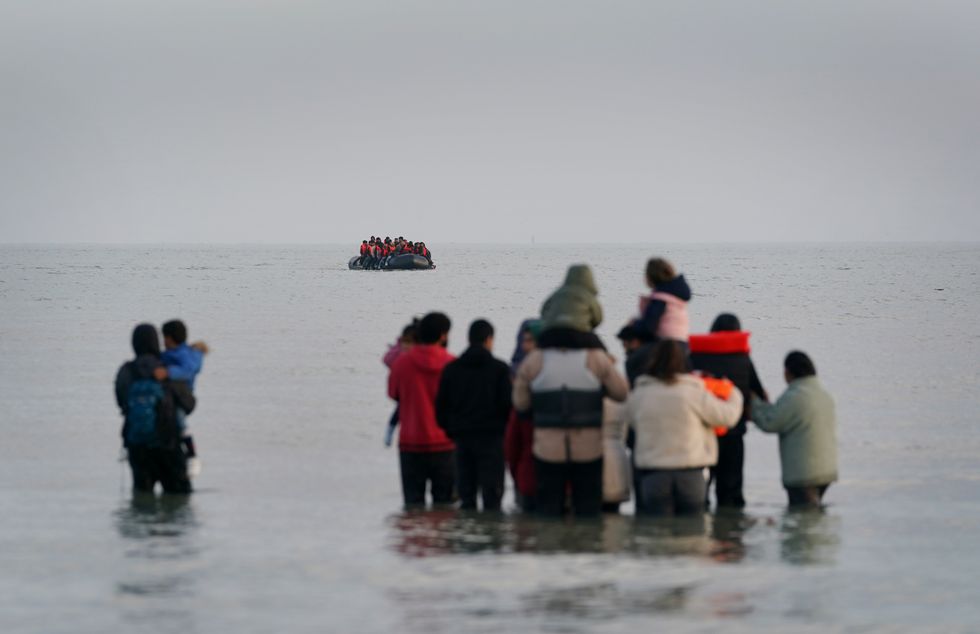 A group of people thought to be migrants wait in the sea to board an approaching small boat at Gravelines, France, in an attempt to reach the UK by crossing the English Channel