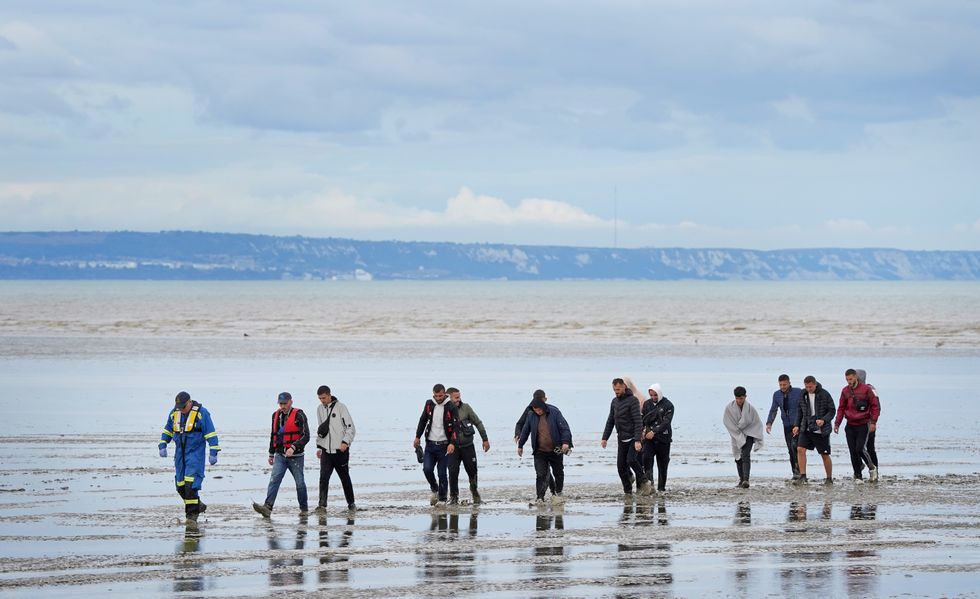 A group of people thought to be migrants walk ashore in Dungeness, Kent, after being intercepted by the Dungeness Lifeboat following a small boat incident in the Channel.