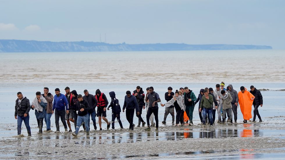 A group of people thought to be migrants walk ashore in Dungeness, Kent, after being intercepted by the Dungeness Lifeboat following a small boat incident in the Channel. Picture date: Thursday August 25, 2022.