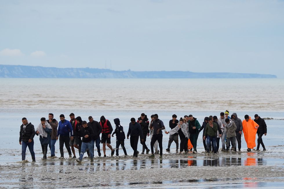 A group of people, thought to be migrants, walk ashore in Dungeness, Kent, following a small boat incident in the Channel. Picture date: Thursday August 25, 2022.