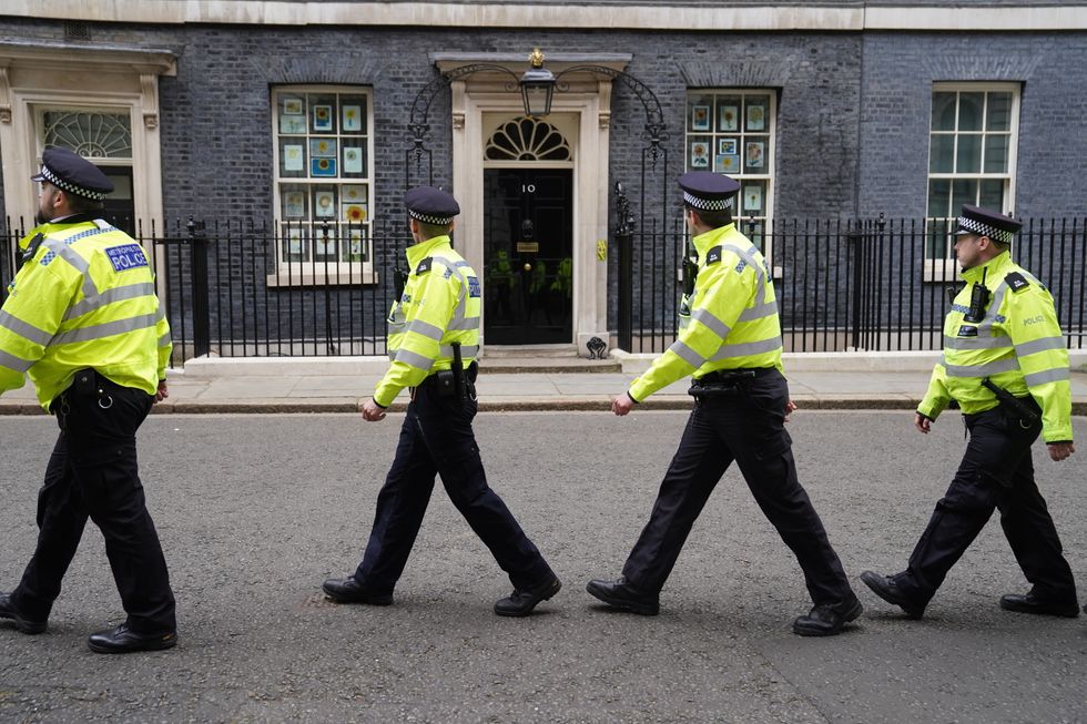 A group of police officers walk through Downing Street, in Westminster, London, during a protest outside the gates.